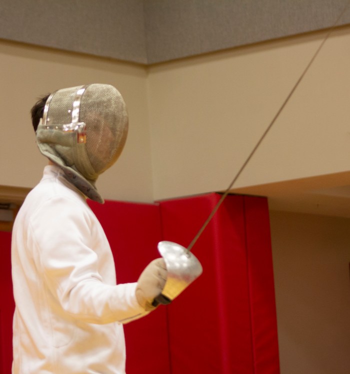 Spencer Deats cloaked in all white and a sabre in his hand, prepares to slash another club member during practice.